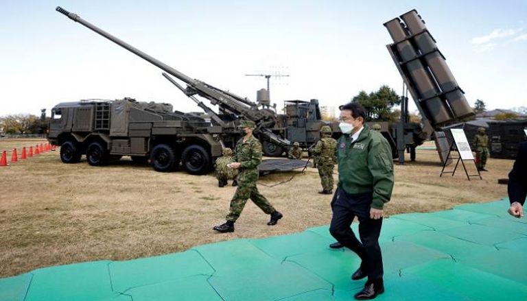 رئيس وزراء اليابان بجوار أسلحة وصواريخ للجيش