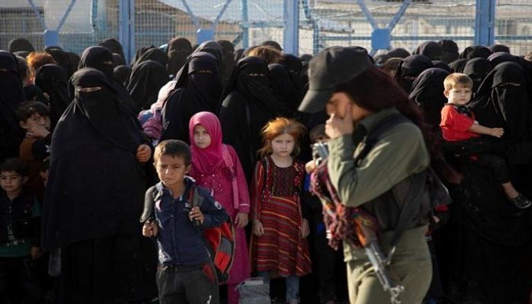 داعشيات وأطفالهن في حراسة إحدى المقاتلات الكرديات- رويترز