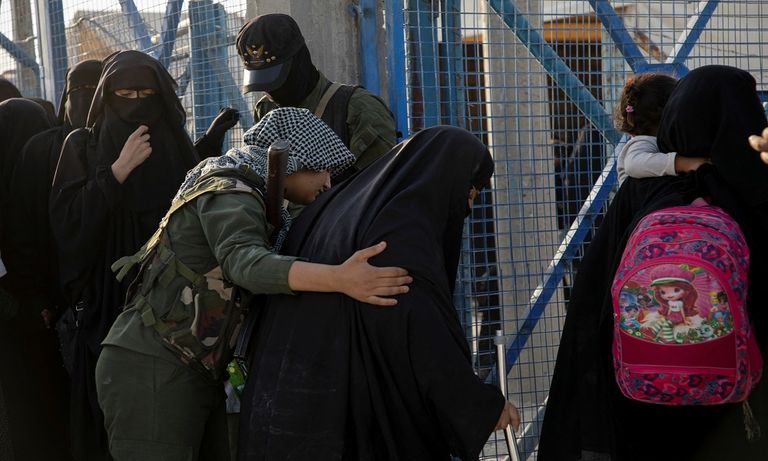 داعشيات وأطفالهن في حراسة إحدى المقاتلات الكرديات- رويترز