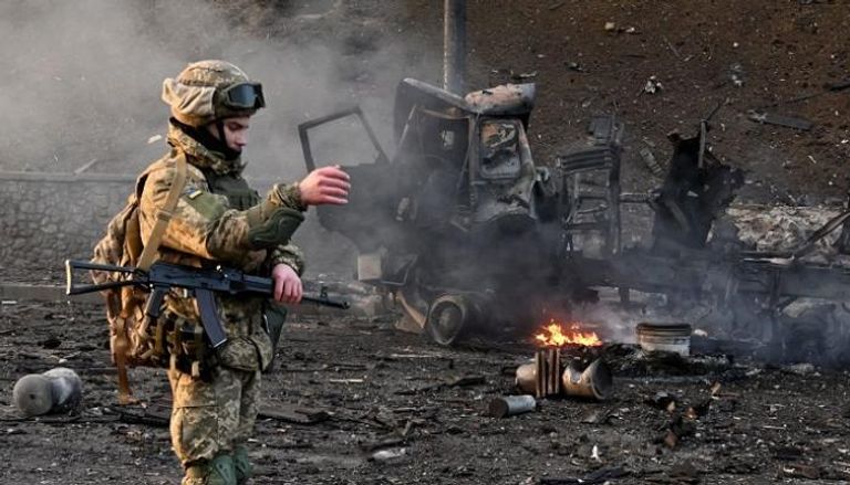 جندي أوكراني بجوار آليات روسية محطمة