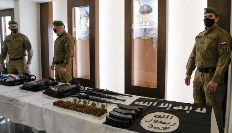 قوات خاصة لبنانية بجوار طاولة عليها علم داعش وأحزمة ناسفة بعد مصادرتها
