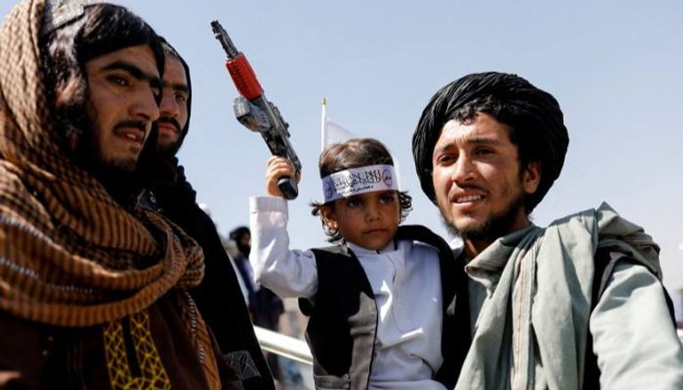 عنصر من طالبان يحمله ابنه في ذكرى الانسحاب الأمريكي- رويترز