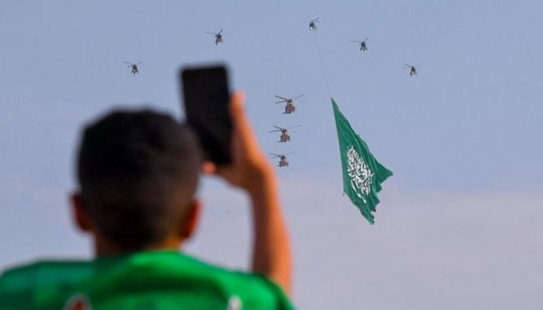 طفل سعودي يلتقط طائرات سعودية تحمل علم المملكة- واس
