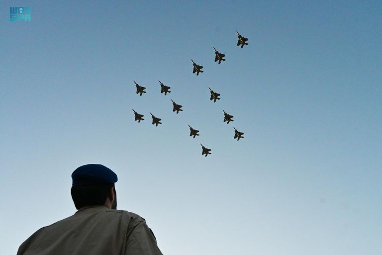 طفل سعودي يلتقط طائرات سعودية تحمل علم المملكة- واس