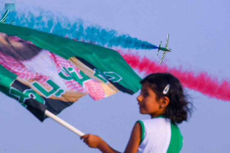 طفل سعودي يلتقط طائرات سعودية تحمل علم المملكة- واس