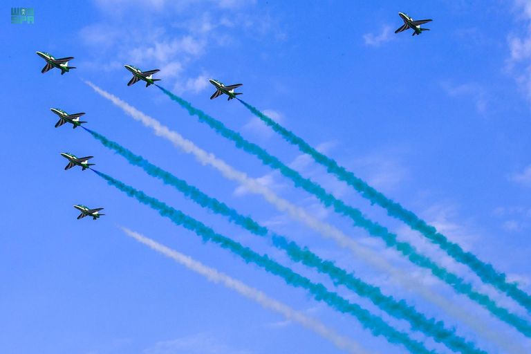 طفل سعودي يلتقط طائرات سعودية تحمل علم المملكة- واس