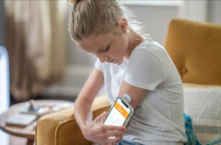 سيدة تضع الكمامة للوقاية من كورونا وبيدها جهاز قياس السكري