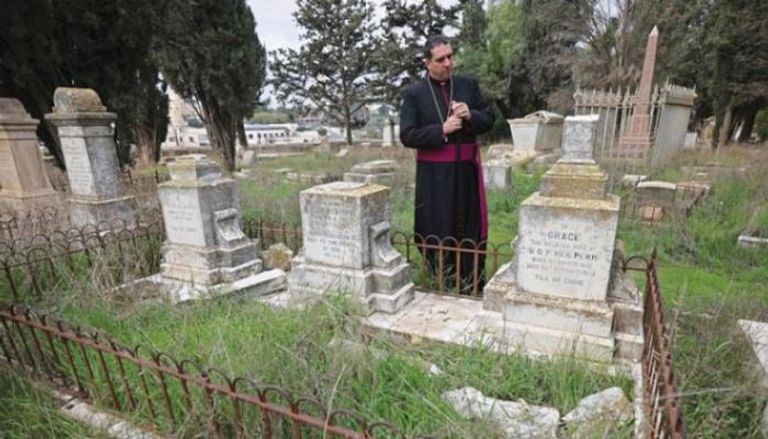 رجل دين يعاين آثار الاعتداء في المقبرة البروتستانتية