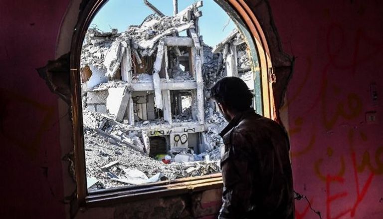 جندي من قوات سوريا الديمقراطية ينظر إلى مبنى دمرته داعش في الرقة