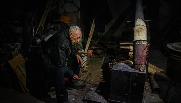 رجل يشعل الحطب في أحد الملاجئ الأوكرانية