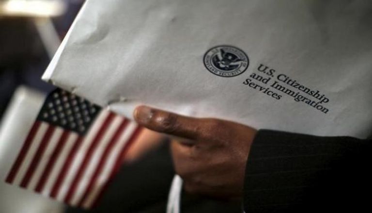 رجل يحمل مظروفا من خدمة المواطنة والهجرة بأمريكا - رويترز