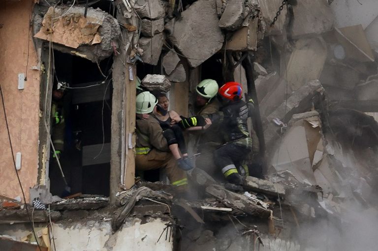 أوكرانيات يتابعن فرق إنقاذ تتعامل مع مبنى تضرر من قصف روسي