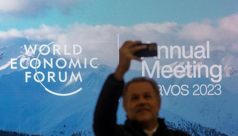 رجل يلتقط صورة أمام شعار المنتدى الاقتصادي العالمي في دافوس