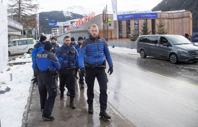 رجل يلتقط صورة أمام شعار المنتدى الاقتصادي العالمي في دافوس