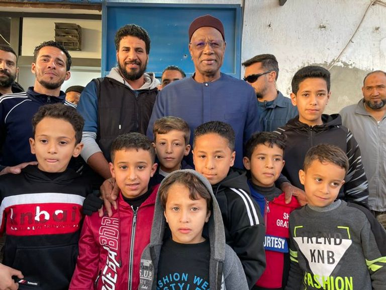 باتيلي أمام منازل دمرها الصراع في سرت