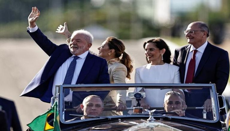 رئيس البرازيل لولا دا سيلفا وزوجته جانجا يلوحان لأنصارهما من موكب السيارات