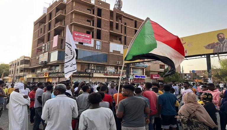 متظاهرون يحملون العلم السوداني في شارع المؤسسة في الخرطوم بالسودان.
