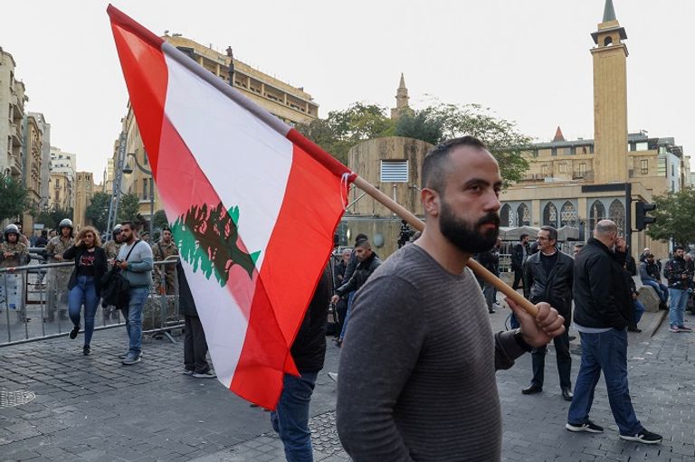 A Lebanese protester carries his country's flag outside the parliament building in Beirut