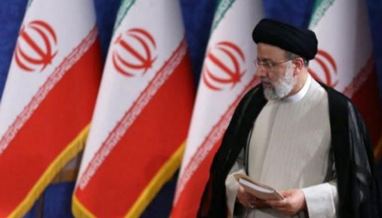 الرئيس الإيراني أمام أعلام بلاده - أرشيفية