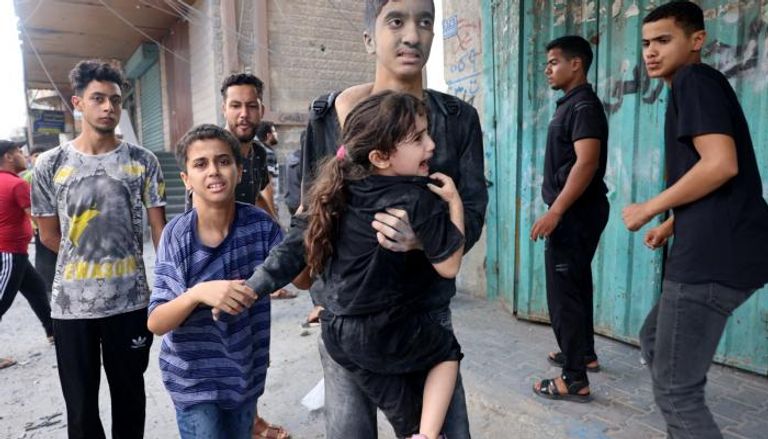 فتى يحمل طفلة صغيرة إثر غارة إسرائيلية على غزة