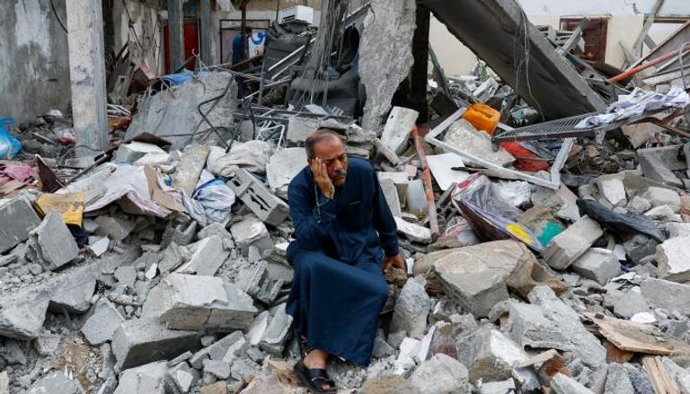فلسطيني يجلس على أنقاض منزله المدمر بفعل القصف
