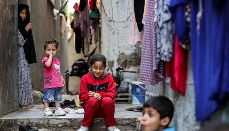 أطفال يجلسون أمام منزلهم في قطاع غزة- أرشيفية