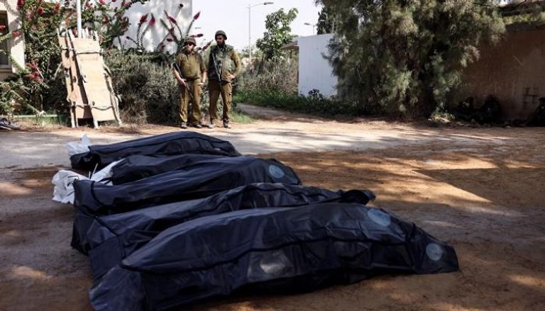 جنديان إسرائيليان يقفان بجوار بعض جثث قتلى هجوم حماس