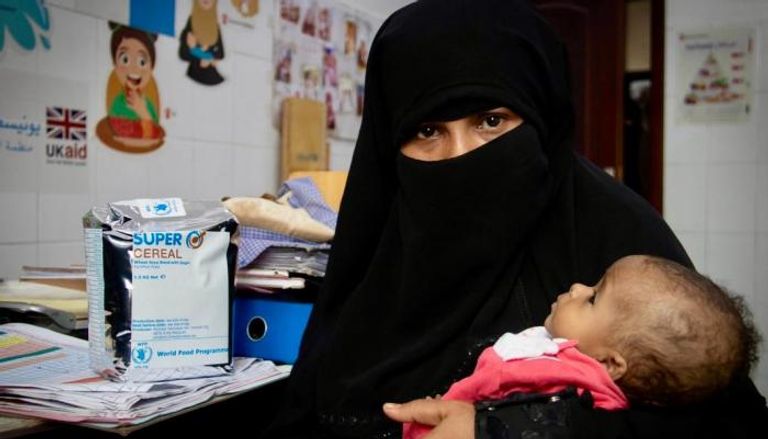 سيدة يمنية مع طفلها الذي يعاني سوء التغذية في أحد المراكز الصحية. - أرشيفية
