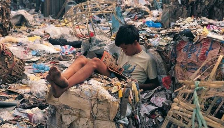 طفل يقرأ وسط القمامة