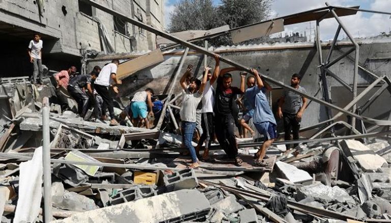 فلسطينيون يرفعون أنقاض مبنى دمره قصف إسرائيلي بغزة - رويترز