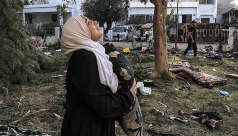 فلسطينية تبكي وهي تحمل وسادة وتقف وسط الأنقاض