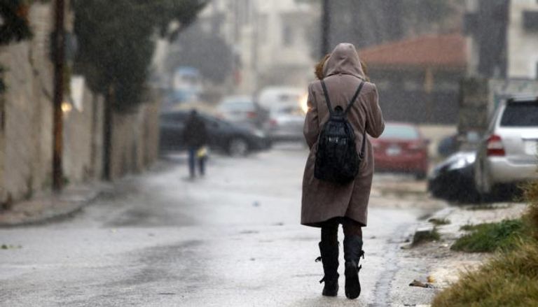 مغربية تحتمي من المطر بمعطفها - أرشيفية