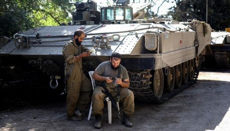 جنديان إسرائيليان بجوار دبابة على حدود غزة - رويترز