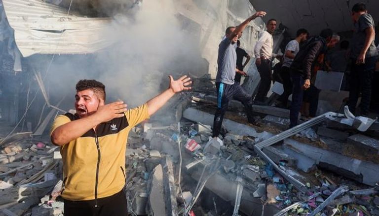 فلسطينيون يقفون وسط حطام منزل دمره قصف إسرائيلي بغزة - رويترز