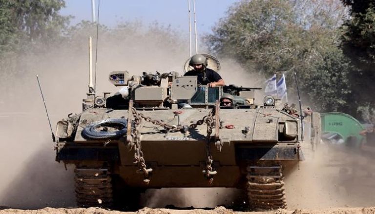 جنود يركبون مدرعة أثناء تحركها إلى موقع قريب من الحدود الإسرائيلية مع غزة