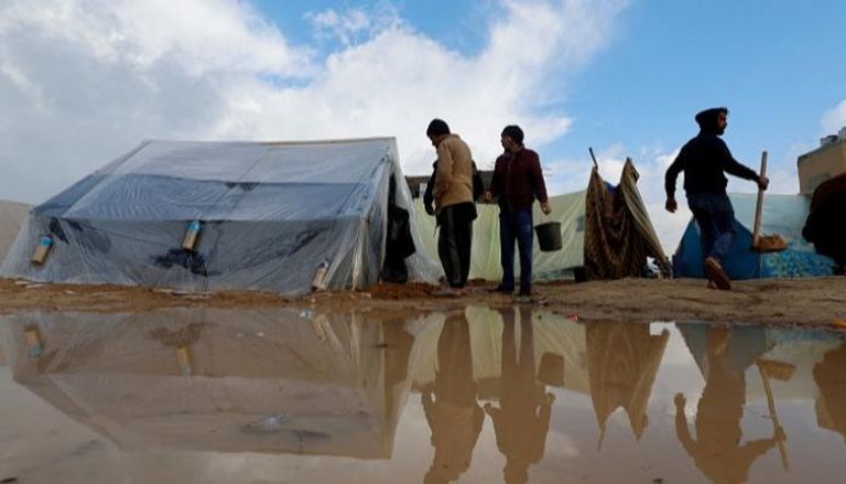فلسطينيون يزيحون مياه الأمطار من خيام في رفح - رويترز