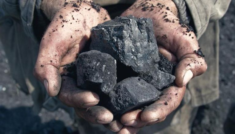 عامل يحمل في يده قطع من الفحم - أرشيفية
