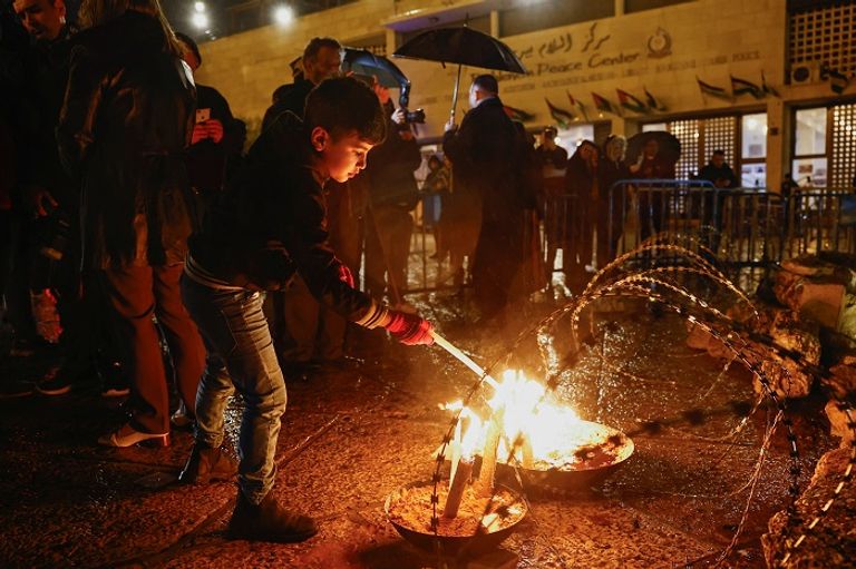 طفل فلسطيني يوقد شمعة بساحة كنيسة المهد - رويترز تماثيل في ساحة كنيسة المهد ببيت لحم تحمل أكفانا رمزية - رويترز