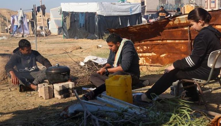 نازحون في قطاع غزة يطبخون على النار في أحد المخيمات - رويترز