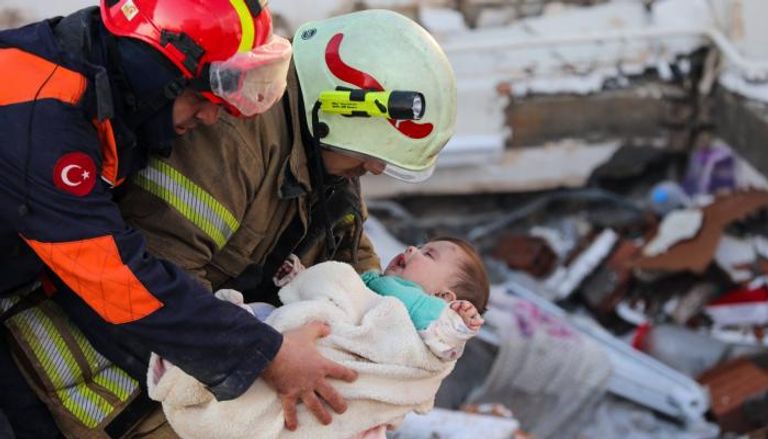 رجلا إنقاذ يحملان الرضيعة بعد إنقاذها
