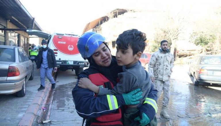 إماراتية تحمل طفلا سوريا بعد إنقاذه من تحت الأنقاض بتركيا