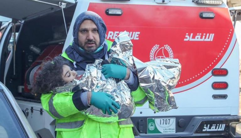 أحد أعضاء فريق الإنقاذ الإماراتي يحمل طفلة انتُشِلت من تحت الأنقاض