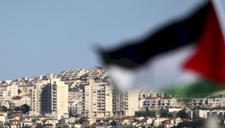 علم فلسطين وعلى الجانب الآخر مستوطنات إسرائيلية