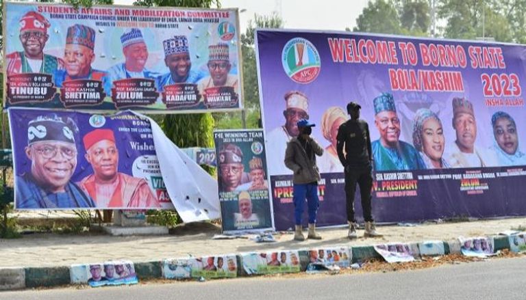 مواطنان نيجيريان أمام لافتات دعائية لمرشحي الرئاسة