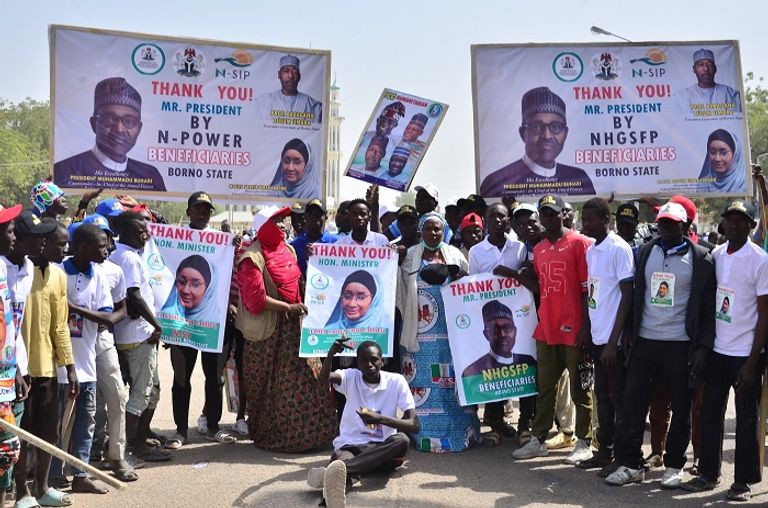 تجمع انتخابي في نيجيريا مواطنان نيجيريان أمام لافتات دعائية لمرشحي الرئاسة