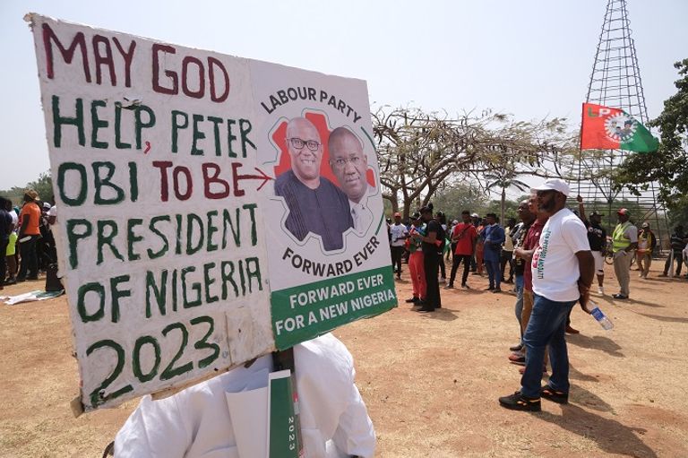أنصار المرشح أوبي يرفعون صوره مواطنان نيجيريان أمام لافتات دعائية لمرشحي الرئاسة