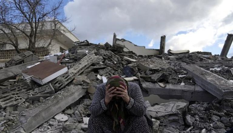 امرأة تركية تجلس على أنقاض منزلها المدمر