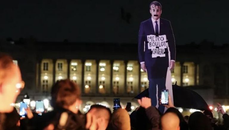 محتجون يرفعون مجسما ورقيا لماكرون في باريس