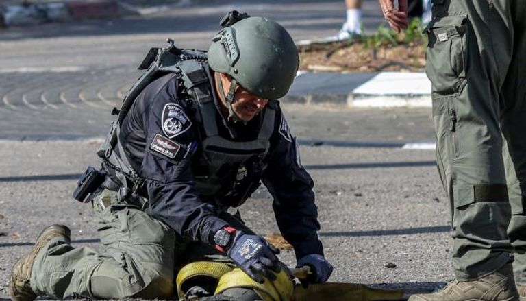 شرطي إسرائيلي يتفقد بقايا قذيفة أطلقت من لبنان