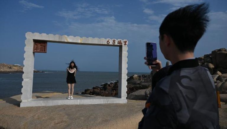 رجل يلتقط صورة لامرأة تحت إطار أمام مضيق تايوان